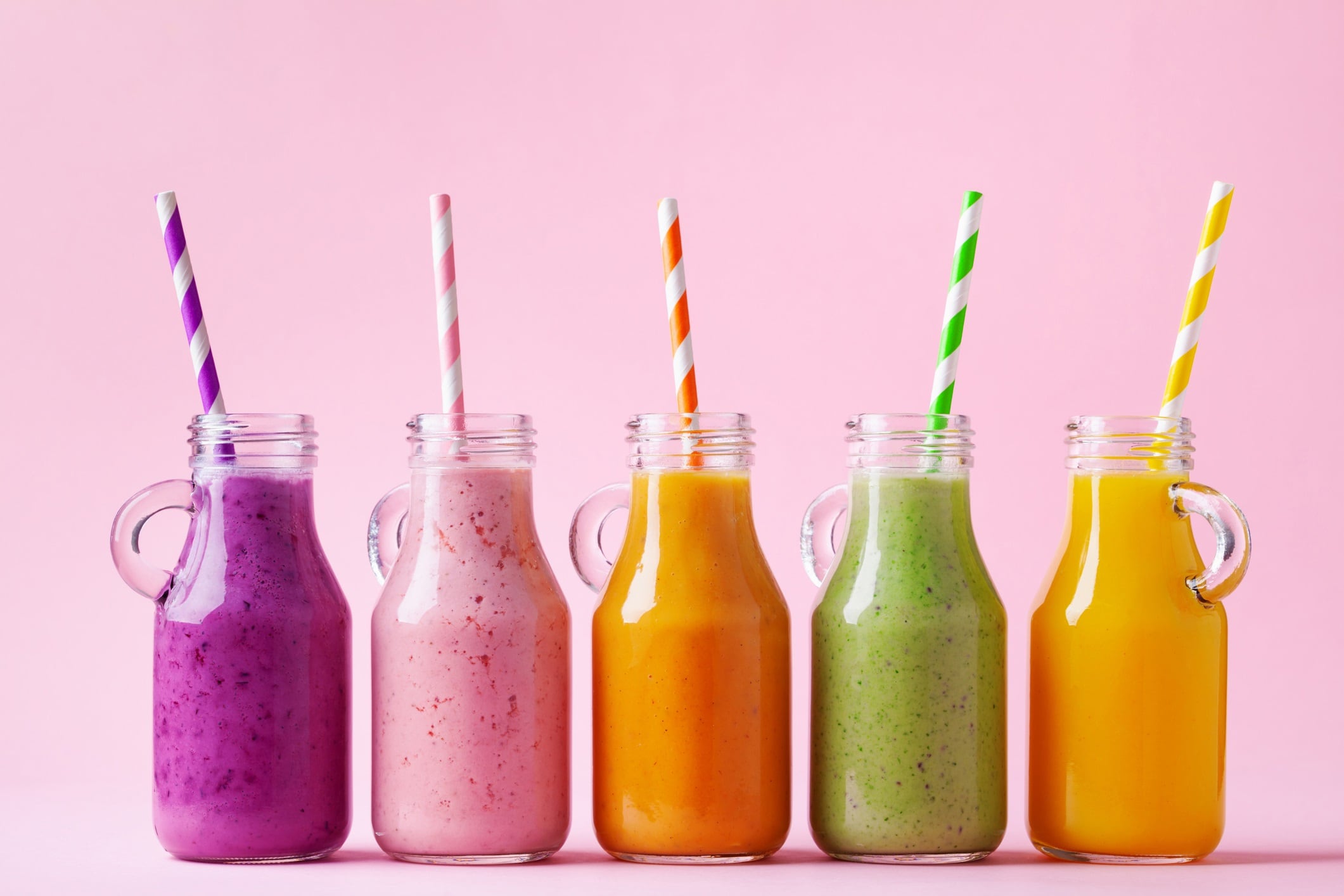Summer colorful fruit smoothies in jars on pink background. Healthy, detox, vegetarian and diet food concept.